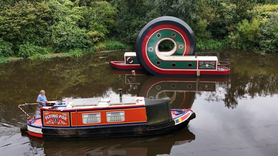 A canal boat passes the looping structure on the Sheffield and Tinsley Canal