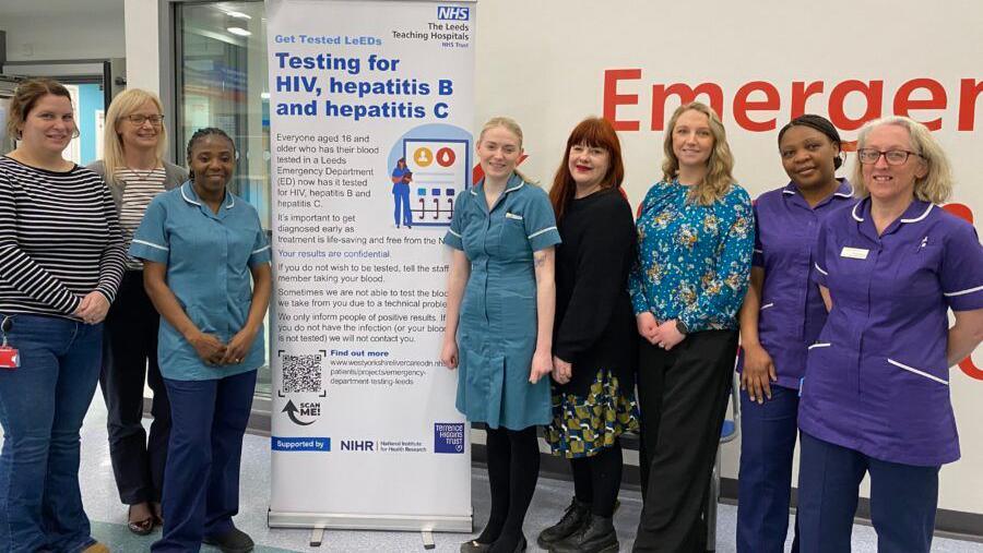 Hospital staff standing next to a pop-up banner about testing.