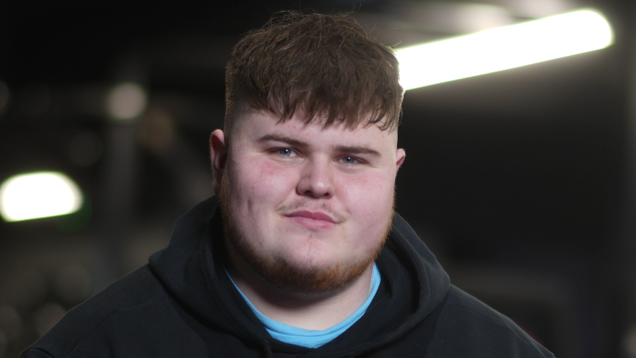 Cleverley smiles at the camera. His brown hair rests over his forehead. He wears a black hoodie with a blue top underneath.