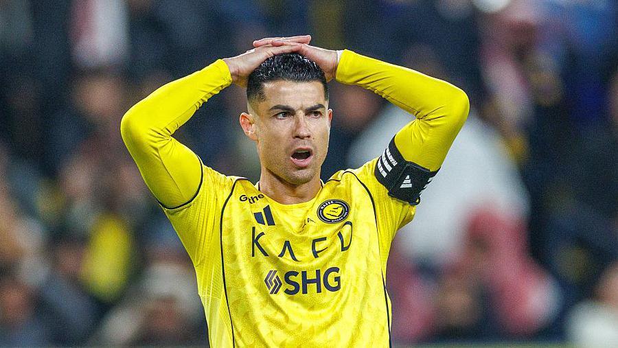 Close-up photograph of Cristiano Ronaldo, playing for Al-Nassr. He has his hands on his head and is wearing the captain's armband