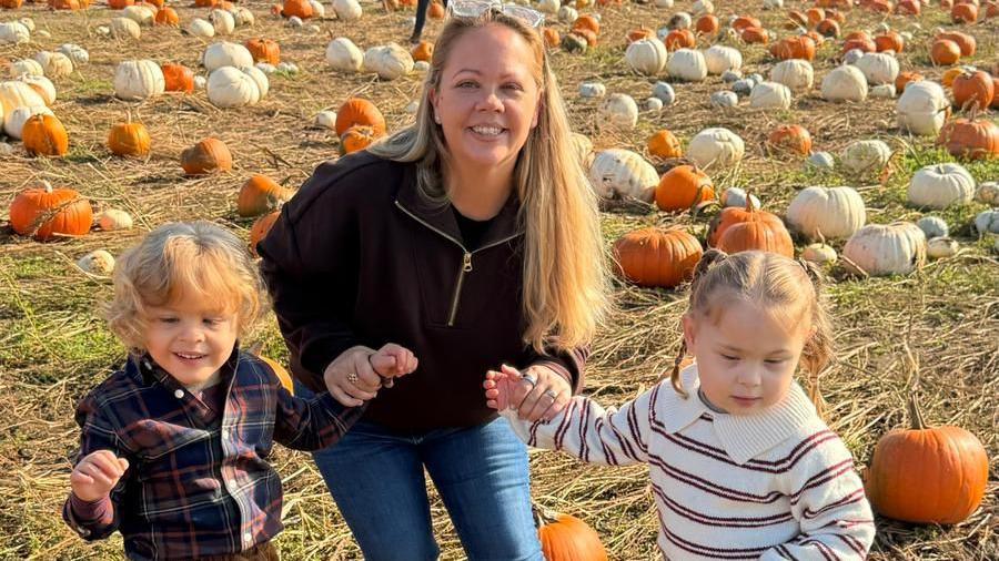 Mum Jade in the middle with Harry on the left and Harley on the right. They are stood in the middle of a pumpkin field. 