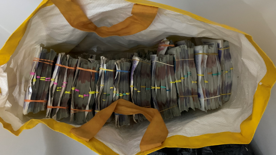 Bundles of British banknotes in elastic bands inside a yellow shopping bag-for-life.