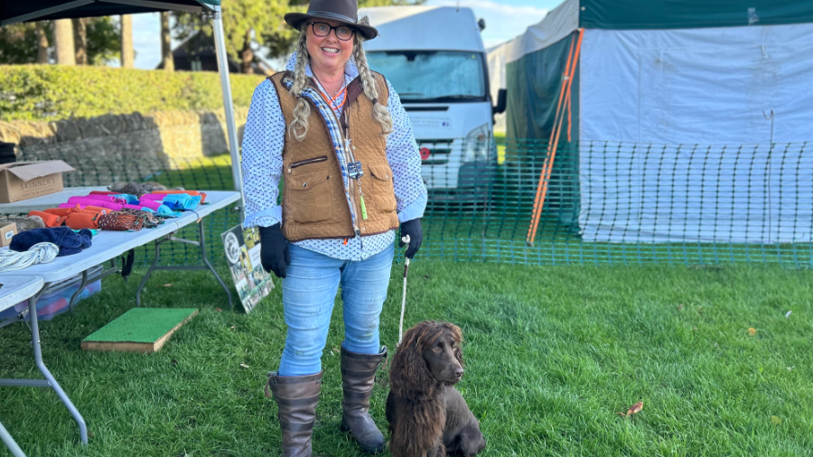 A lady dressed in farming attire with her brown gundog.
