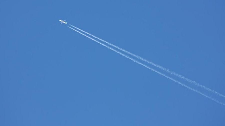 An aeroplane creating vapour trails in the sky on a clear day.