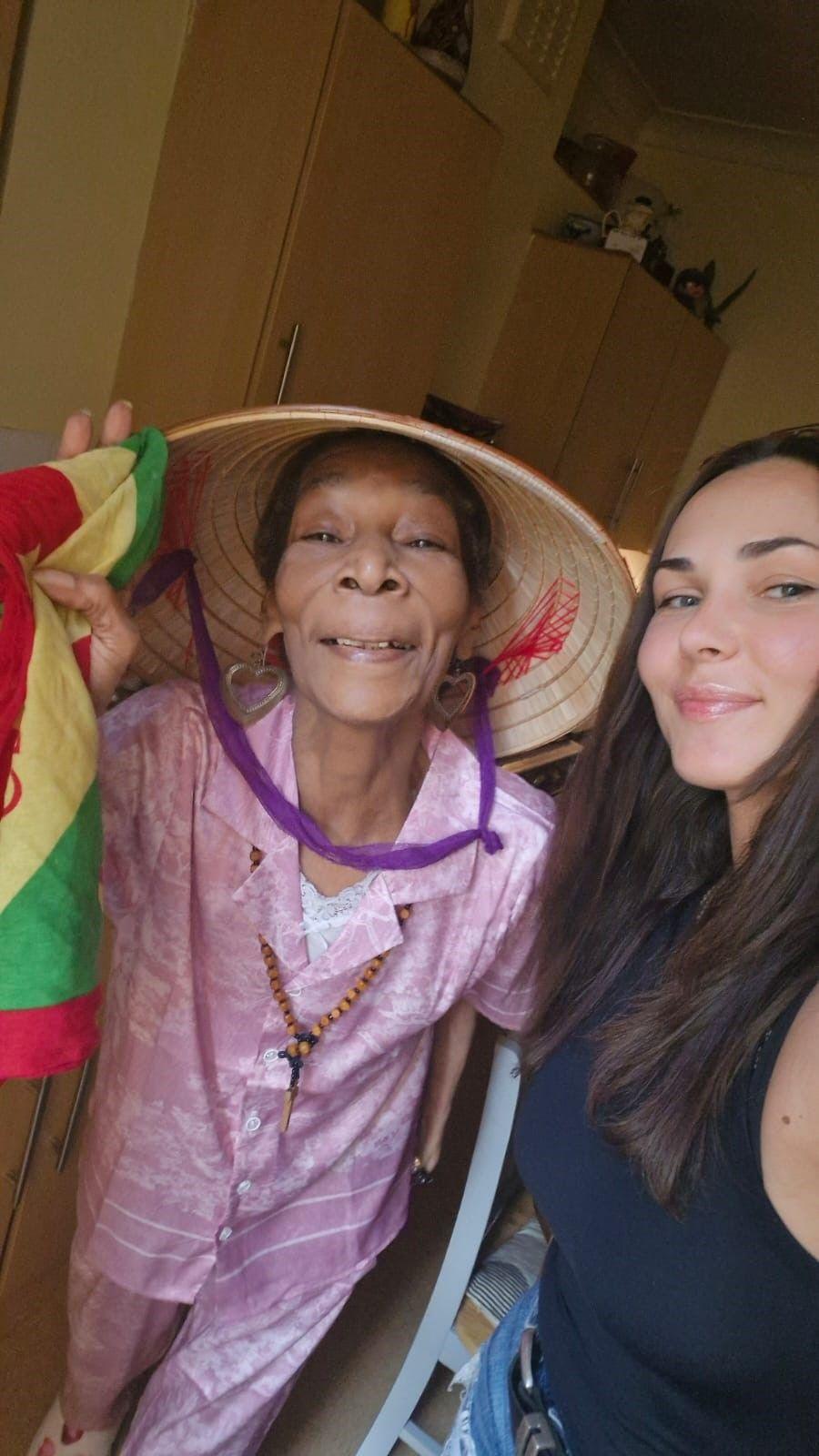 Marline Anderson, a 77-year-old woman in a Vietnamese sun hat, smiles next to a Vasilisa, a young woman with long dark hair