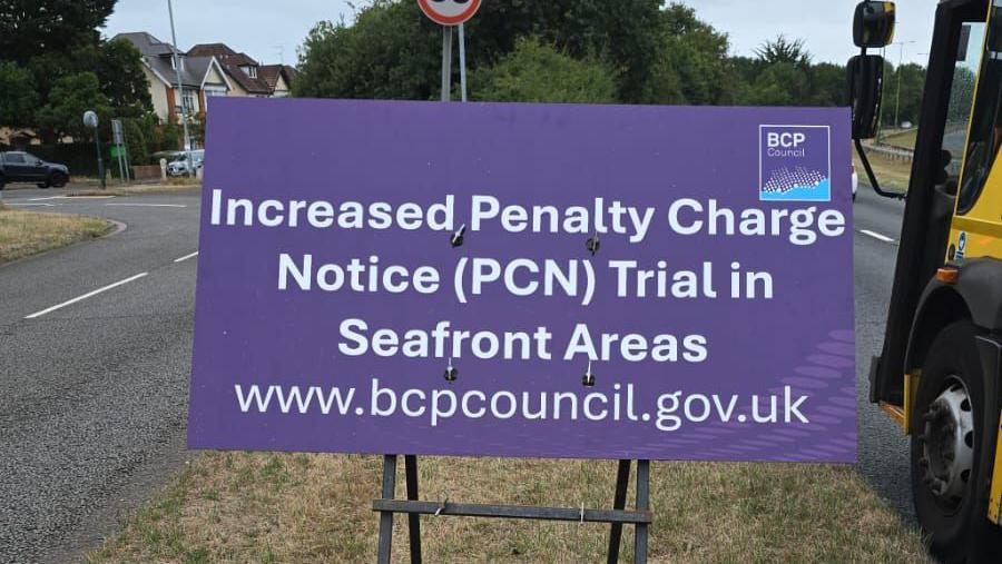A purple sign saying Increased Penalty Charge Notice (PCN) Trial in Seafront Areas