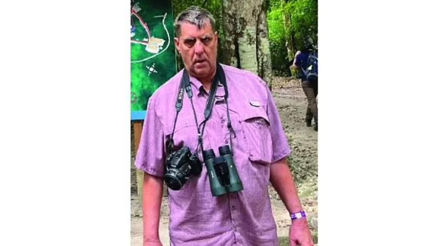 A photo used on one of the missing posters shared by Tikal National Park shows 66-year-old Raymond Ashcroft in a lilac shirt. From his neck hang a photo camera and binoculars. 
