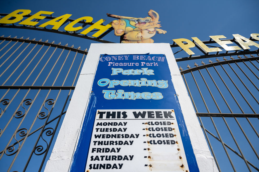 The iron front gates of the funfair. A sign at the front advertises opening times, with the word "closed" next to every day. 