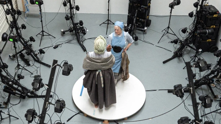 Two women in period dress clasp hands while surrounded by camera equipment. The image is taken from above the women