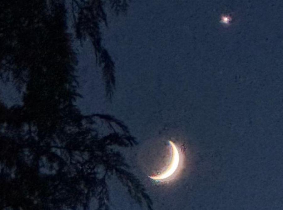 A crescent moon and Venus against a dark sky