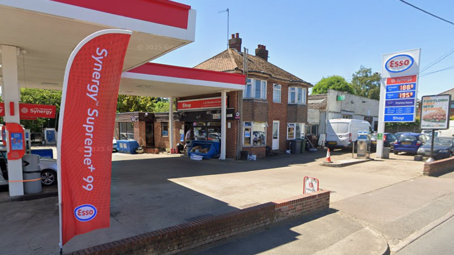 The front of an Esso petrol station forecourt, with a shop that has been built into the side of a detached home.