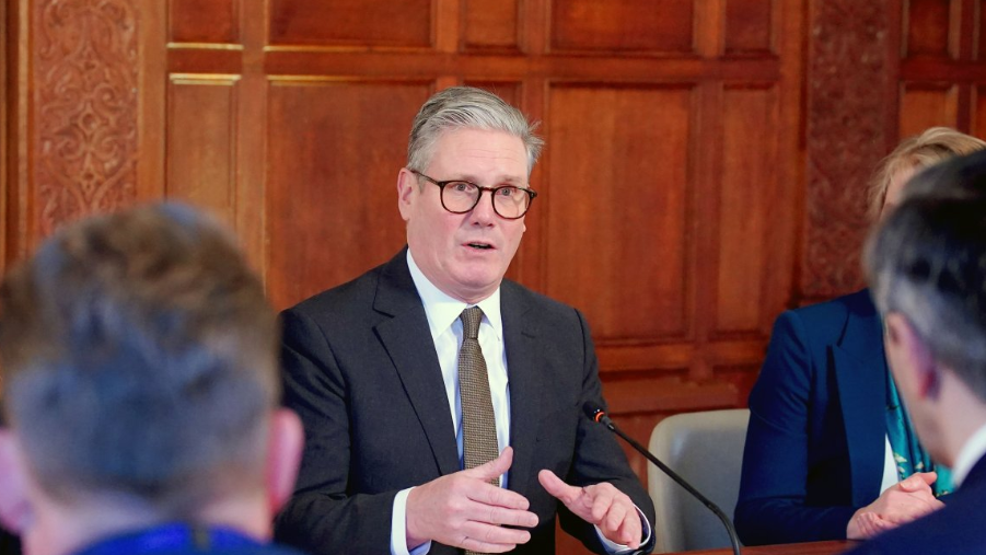 Prime Minister Keir Starmer spaking at the UK-Ireland Summit 2025 at Inglewood Manor House in Ellesmere Port, Liverpool. He wears black rimmed spectacles, a black suit, white shirt and brown tie.