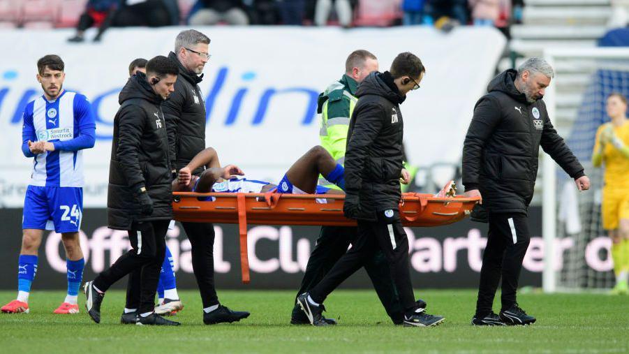 On-loan Wigan Athletic player Silko Thomas is carried off on a stretcher during the League One match against Lincoln City on Saturday