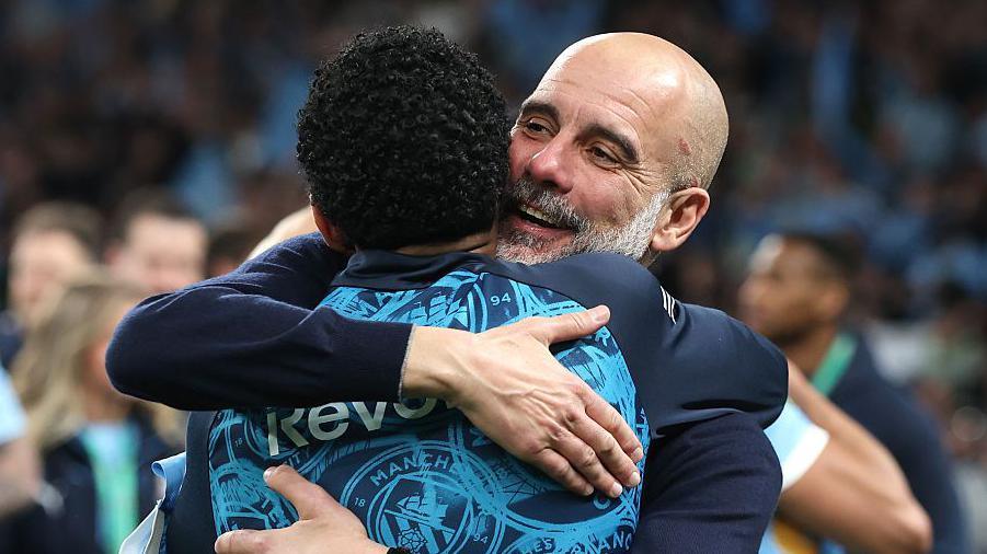 Pep Guardiola hugs his players