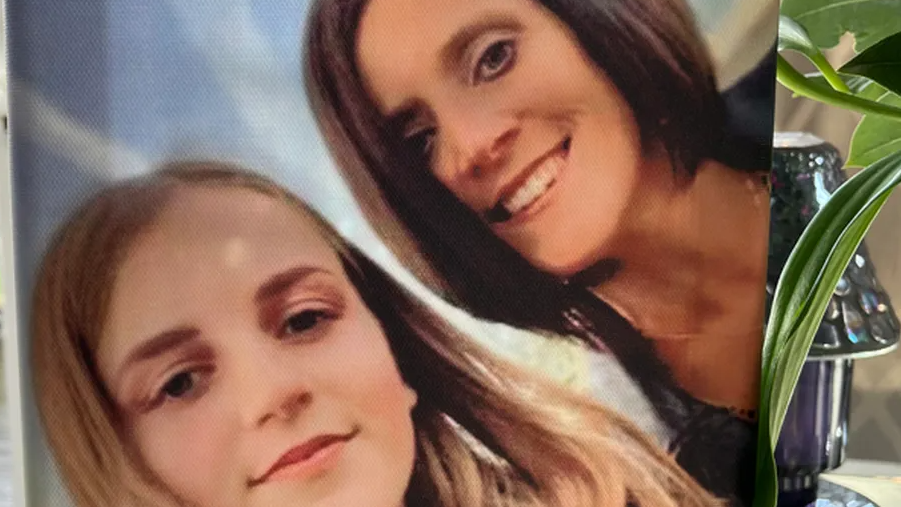 A photograph of a selfie showing Brodie and her mother, propped up on a table lamp