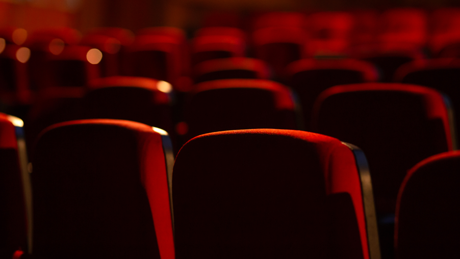 The back of rows of theatre auditorium red seats