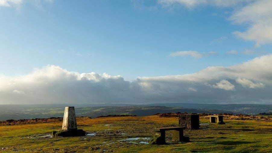Moorland with a white concrete Triangulation Point in the foreground.
