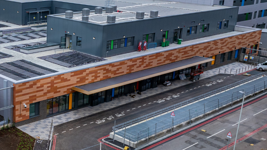 Aerial shot of the outside of Queen Alexandra's emergency department. It has a brown facade with drop-off bays outside.