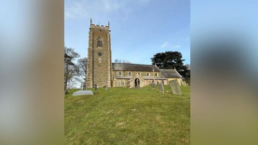 West Keal Church, taken from a distance outside on grass, with gravestones 