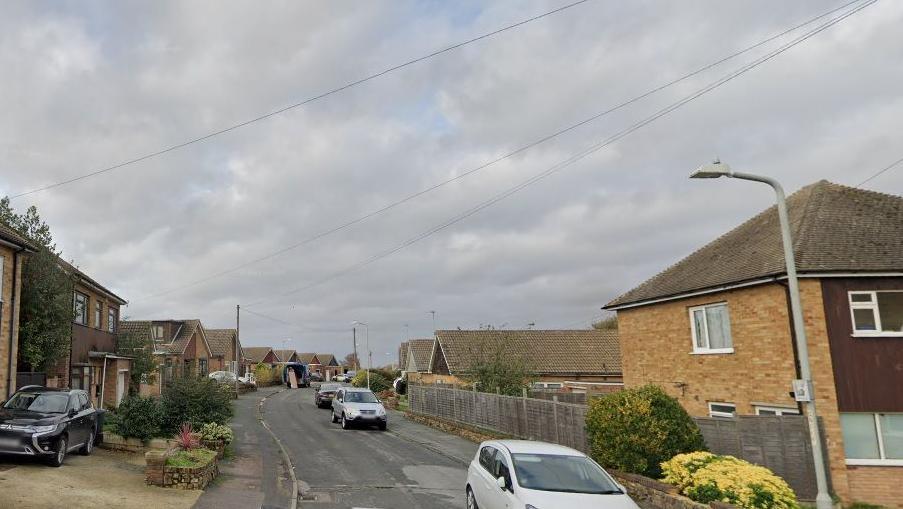 Cerne Road is seen in a Google street view with cars parked along the sides of it. The houses are a mix of bungalows and semi-detached with pitched roofs.