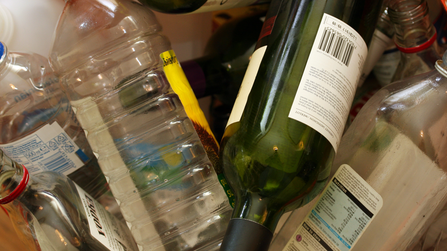 A pile of empty glass and plastic bottles. 