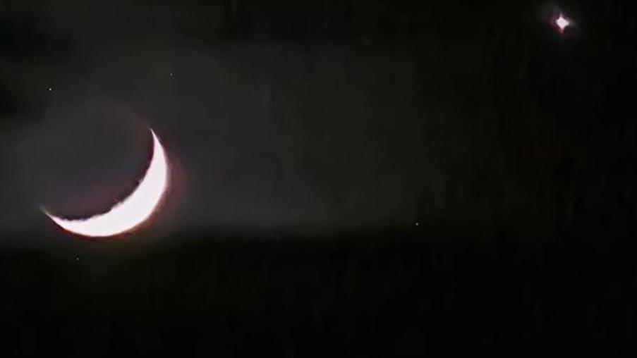 A crescent moon and Venus against a dark sky.