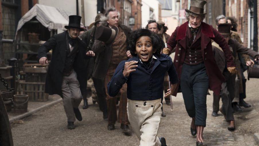 A scene from The Personal History of David Copperfield, directed by Armando Iannucci. Showing actor Jairaj Varsani in Victorian dress being chased by Peter Capaldi.