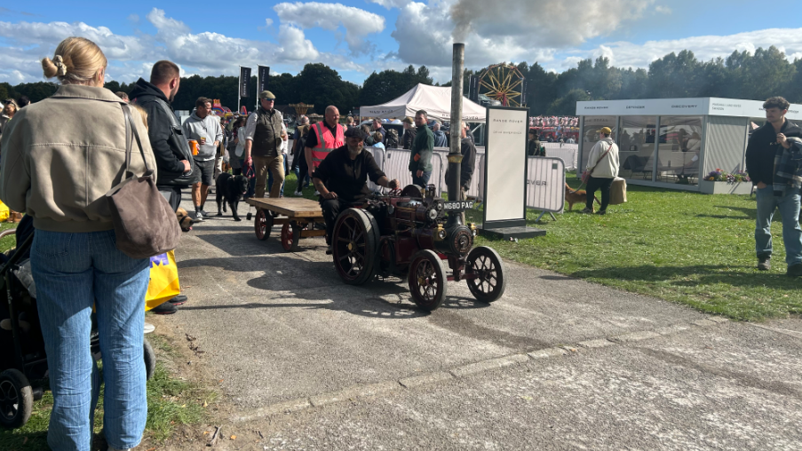Generic image of the county show and the public watching an old machine with steam driving by.