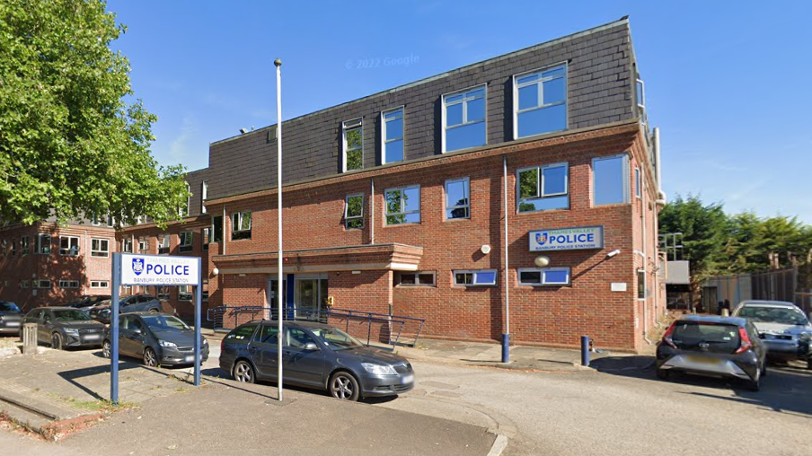 The outside of Banbury police station, a three-storey square brick building with half a dozen cars parked outside.