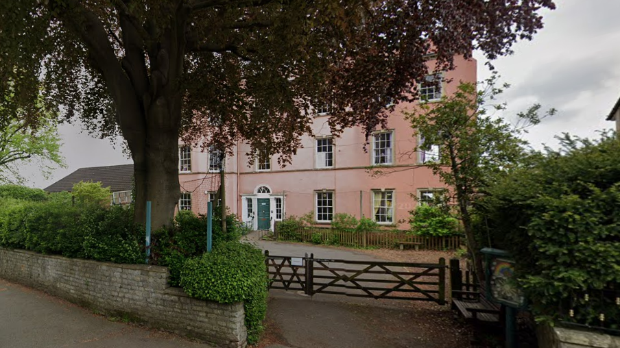 Entrance to pink-coloured school with trees around