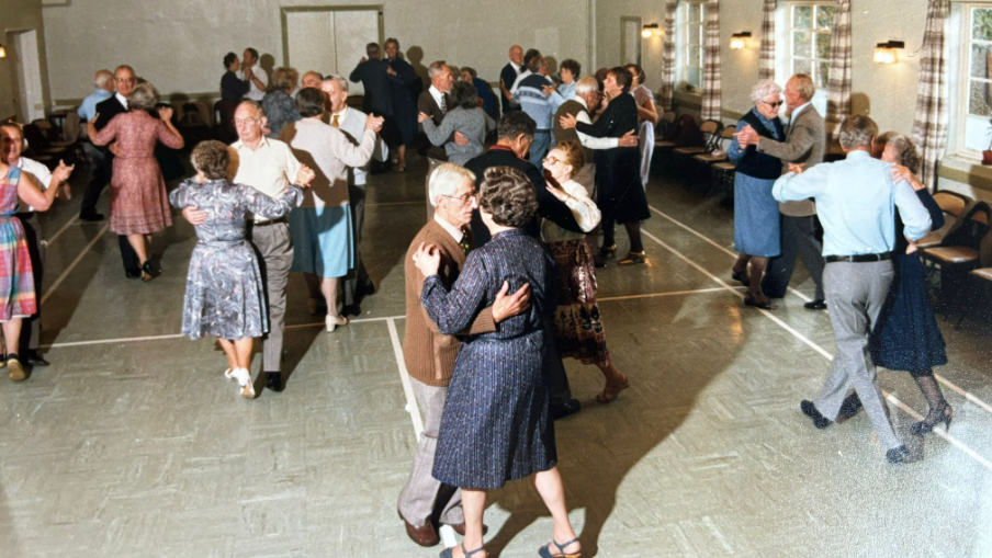 An old photo from the 1970s of couples waltzing at a tea dance in the community centre