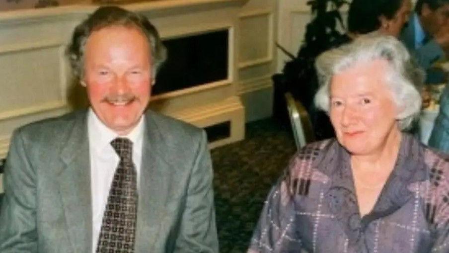 George Phelon in a grey suit and tie next to Frances Phelon in a purple blouse.