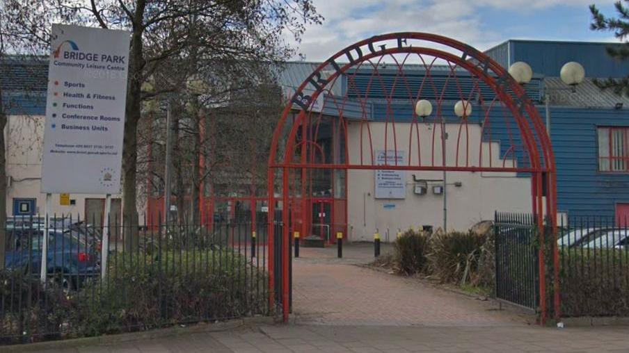 The community centre - a large municipal building with blue cladding and red-painted metalwork