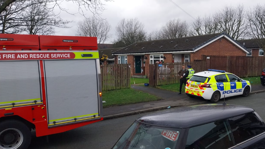 A fire engine and police car at the scene of the fire in a ground floor flat in Oldham