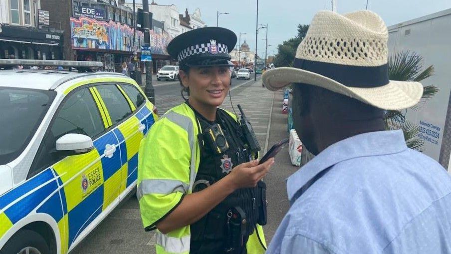 A police officer smiling while talking to a man on the street.