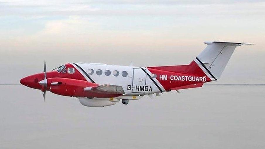 Coastguard red and white fixed wing aircraft in flight