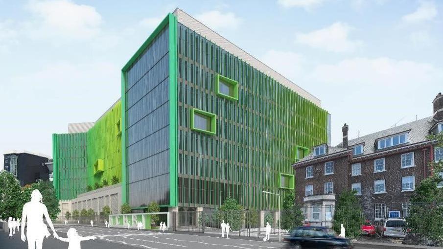 The image is an artist's impression of a new hospital planned for west Belfast. The 10-storey building is glass with a green glint and is beside what look like residential properties. There are the silhouettes of people in the image.