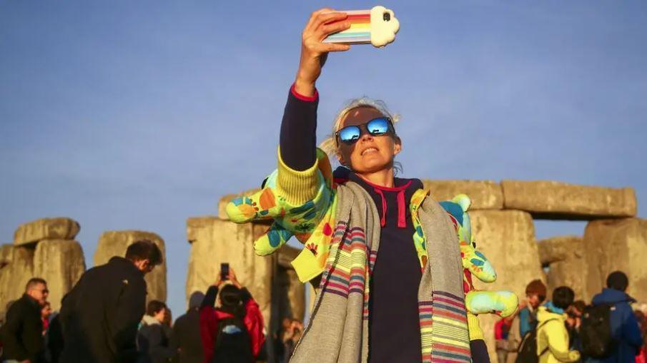 A woman taking a selfie in front of Stonehenge.