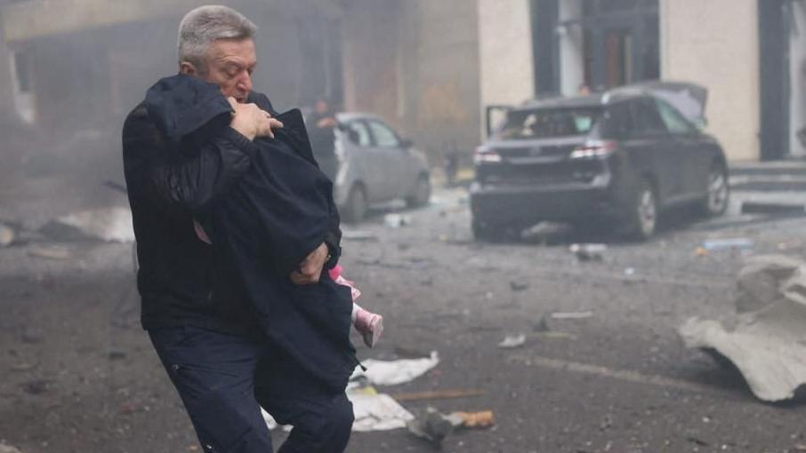 Oleksandr Volobuev carries a young child out of a kindergarten hit by a Russian drone