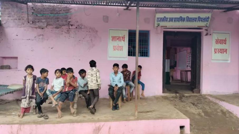 Children sit outside Mr Singh's house, which has pink walls.