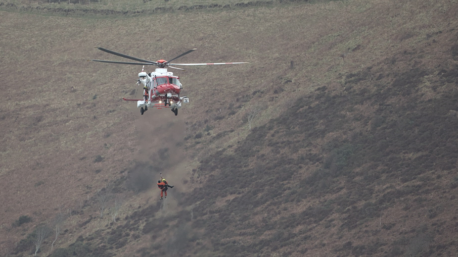 A coastguard helicopter winching a surfer to rescue in Lynmouth, Devon