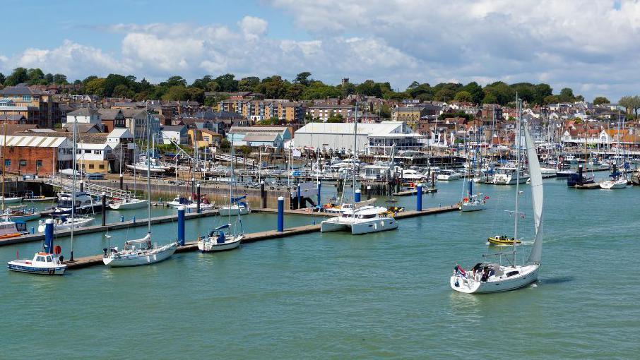 A view of a marina, with boats mooored or sailing around it.