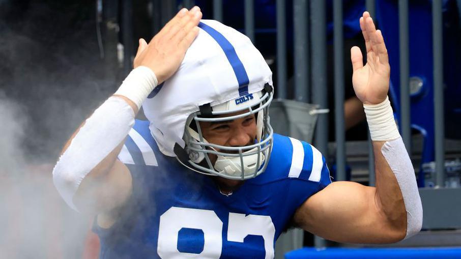 Kylen Granson of the Indianapolis Colts pats his head while wearing a Guardian Cap over his helmet