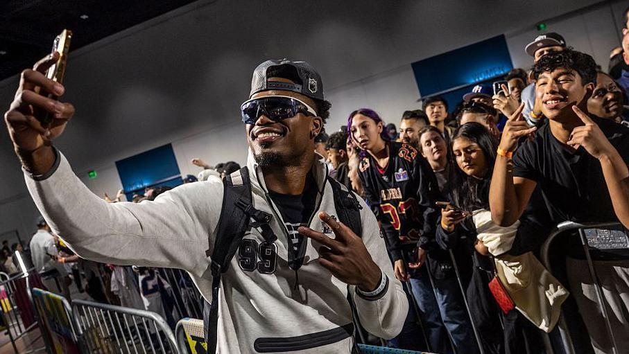 New England Patriots' Amari Gainer poses for a photo with fans during Opening Night for Super Bowl 60