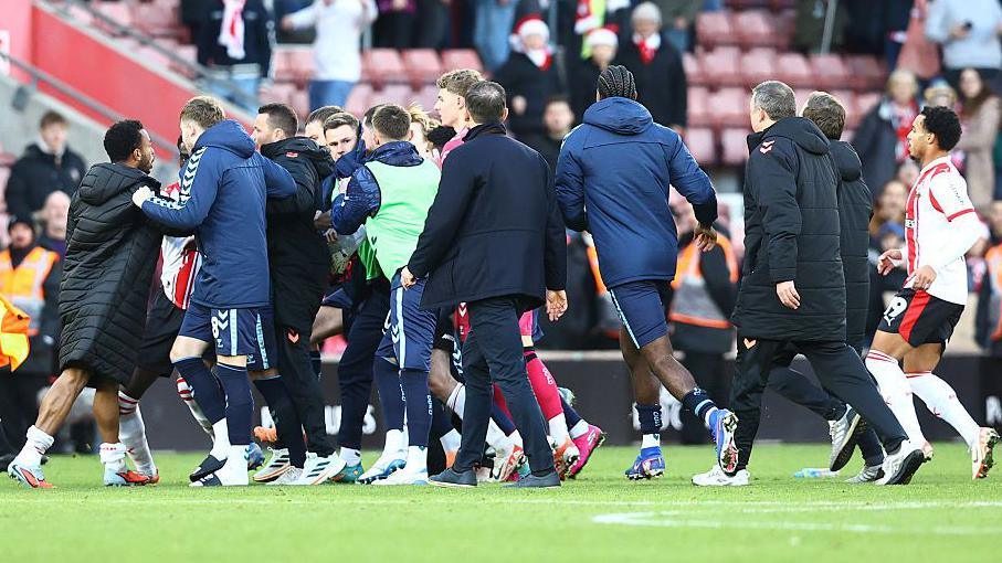 Players from both sides are involved in a melee on the pitch at St Mary's