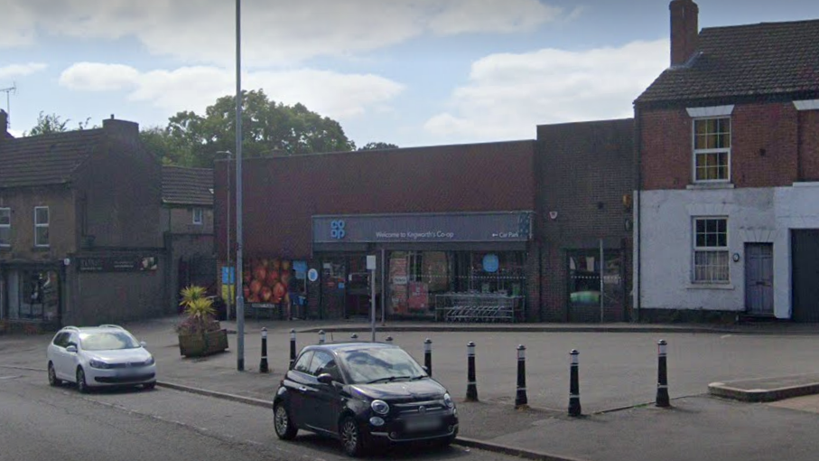 A supermarket in front of a car parking area off a main road segregated by bollards