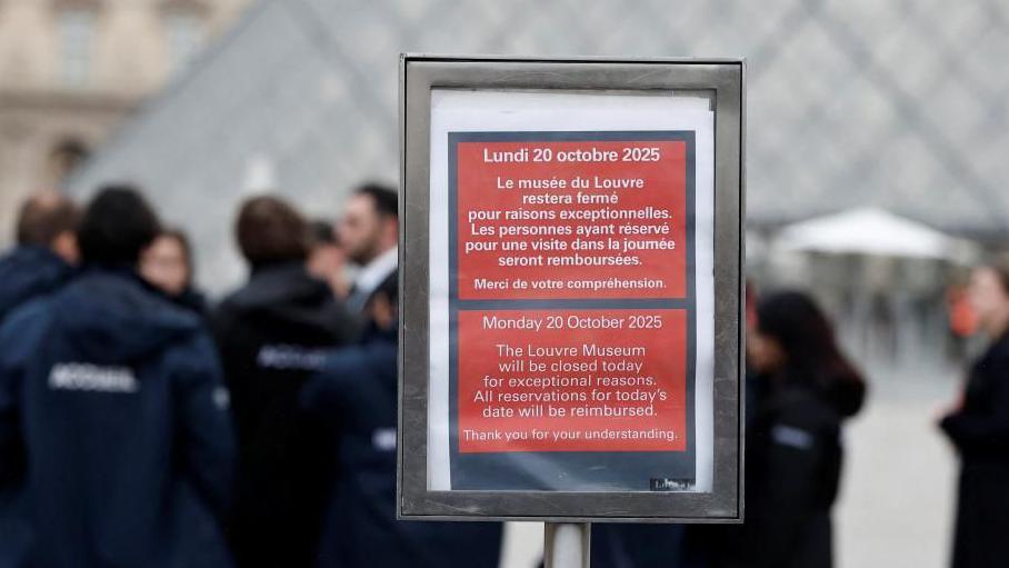 A placard which reads "The Louvre Museum will be closed today for exceptional reasons" in English and French situated near the glass Pyramid of the Louvre Museum.
