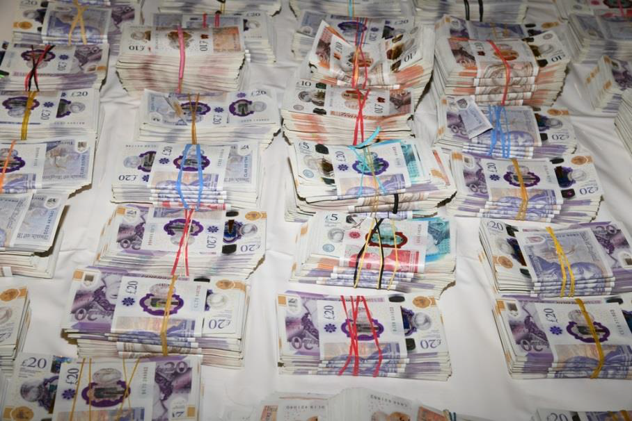 Bundles of bank notes laid out over a white surface.
