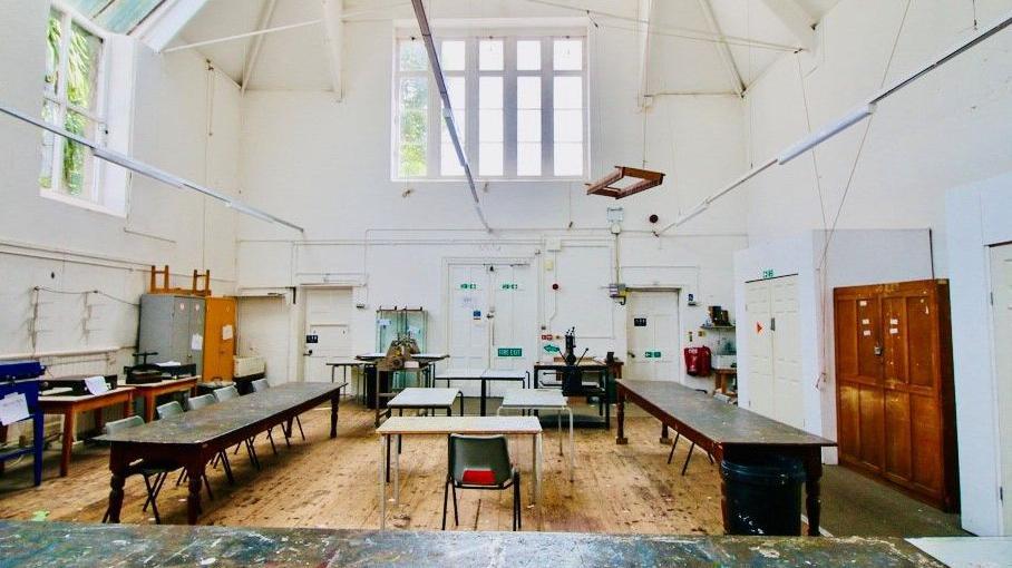 Tall white painted room with large farmhouse tables mixed with modern furniture in a classroom type style
