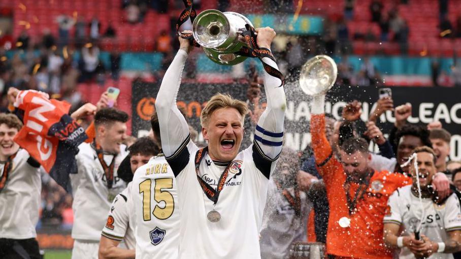 Byron Webster [centre] celebrates with the trophy after Bromley beat Solihull Moors in the National League promotion final